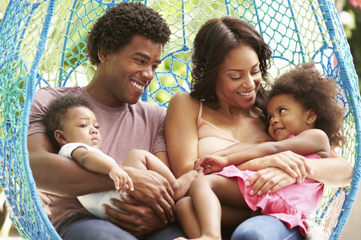 Family Relaxing On Outdoor Garden Swing Seat