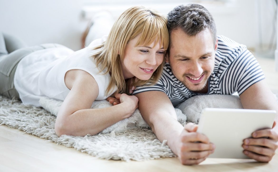 Couple with tablet lying on floor and surfing the net
