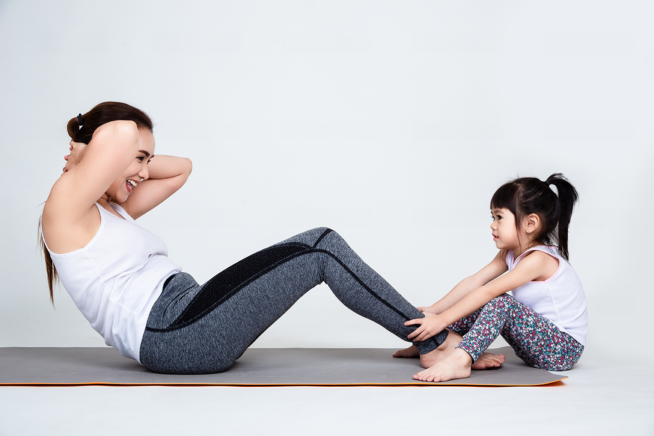 Young mother training lovely daughter with gymnastic