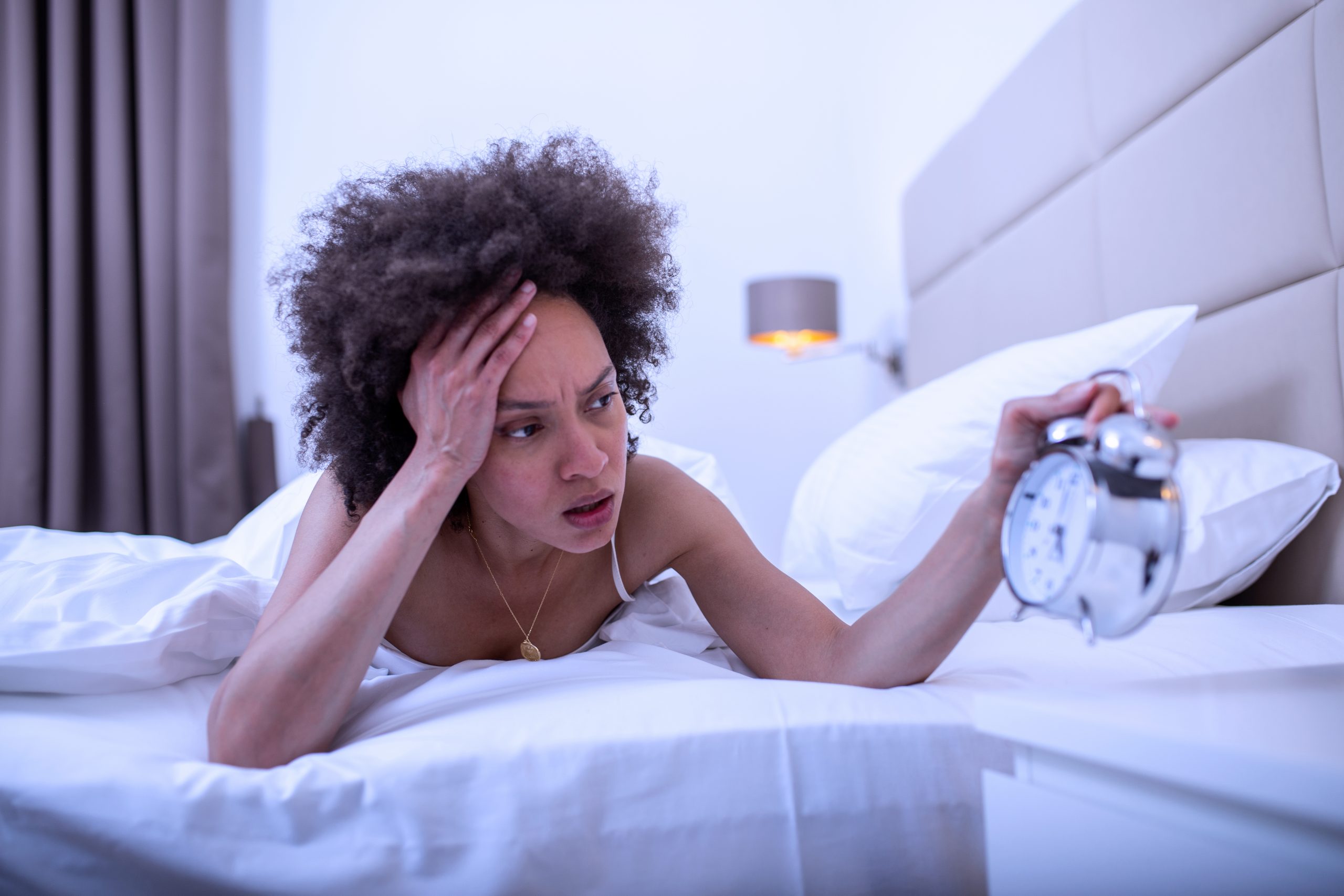 Woman lying in bed suffering from insomnia, Sleepless and desperate beautiful caucasian woman awake at night not able to sleep, feeling frustrated and worried suffering from insomnia in sleep disorder