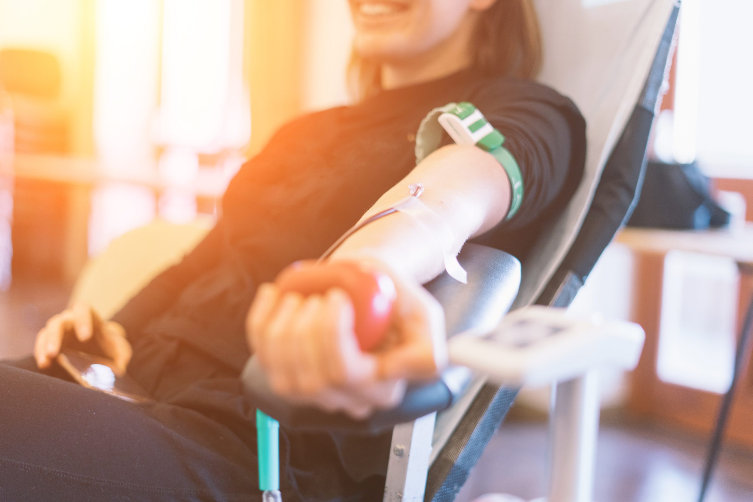 young woman as blood donor at donation with a bouncy ball holdin