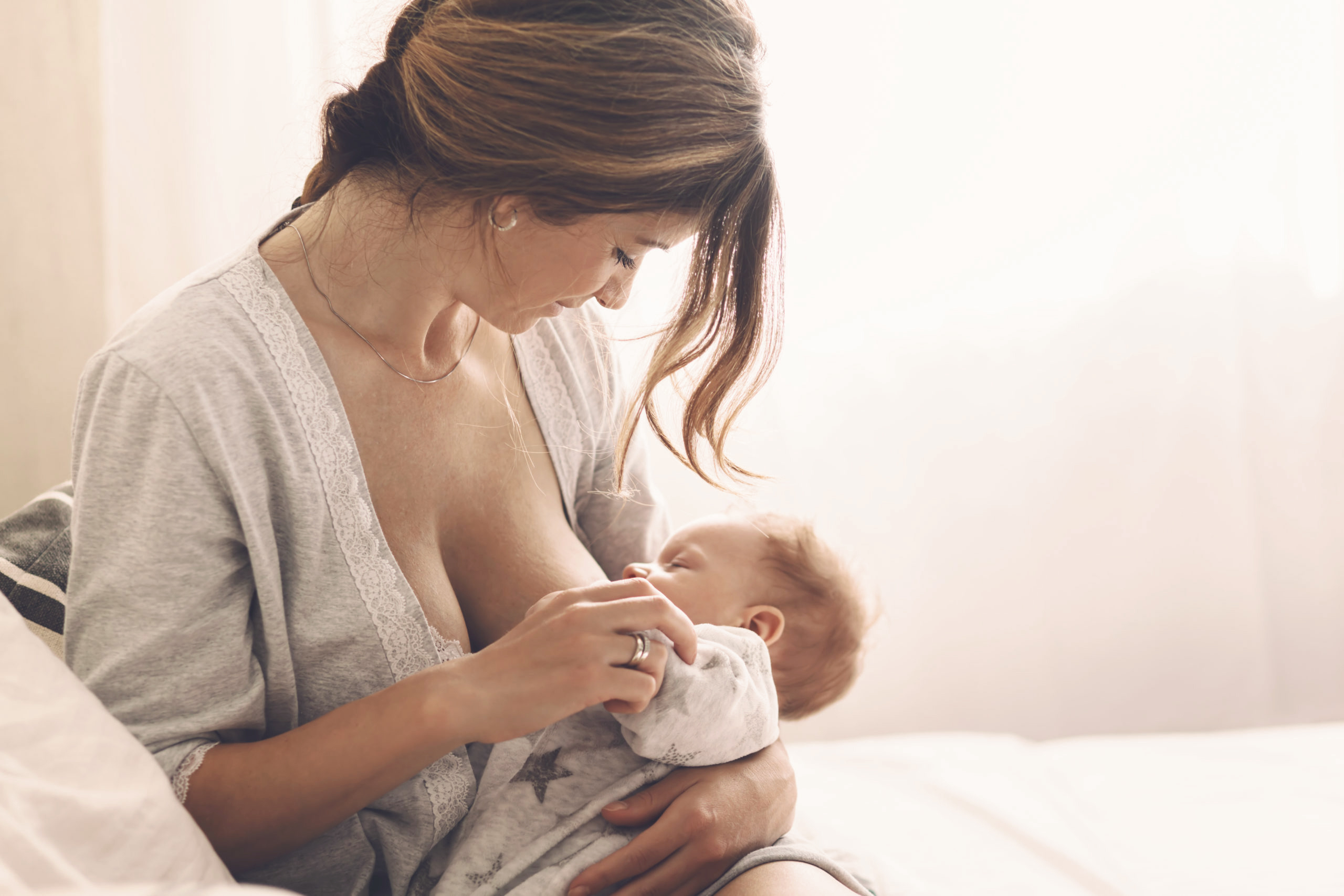 Loving mom breastfeeding her newborn baby at home