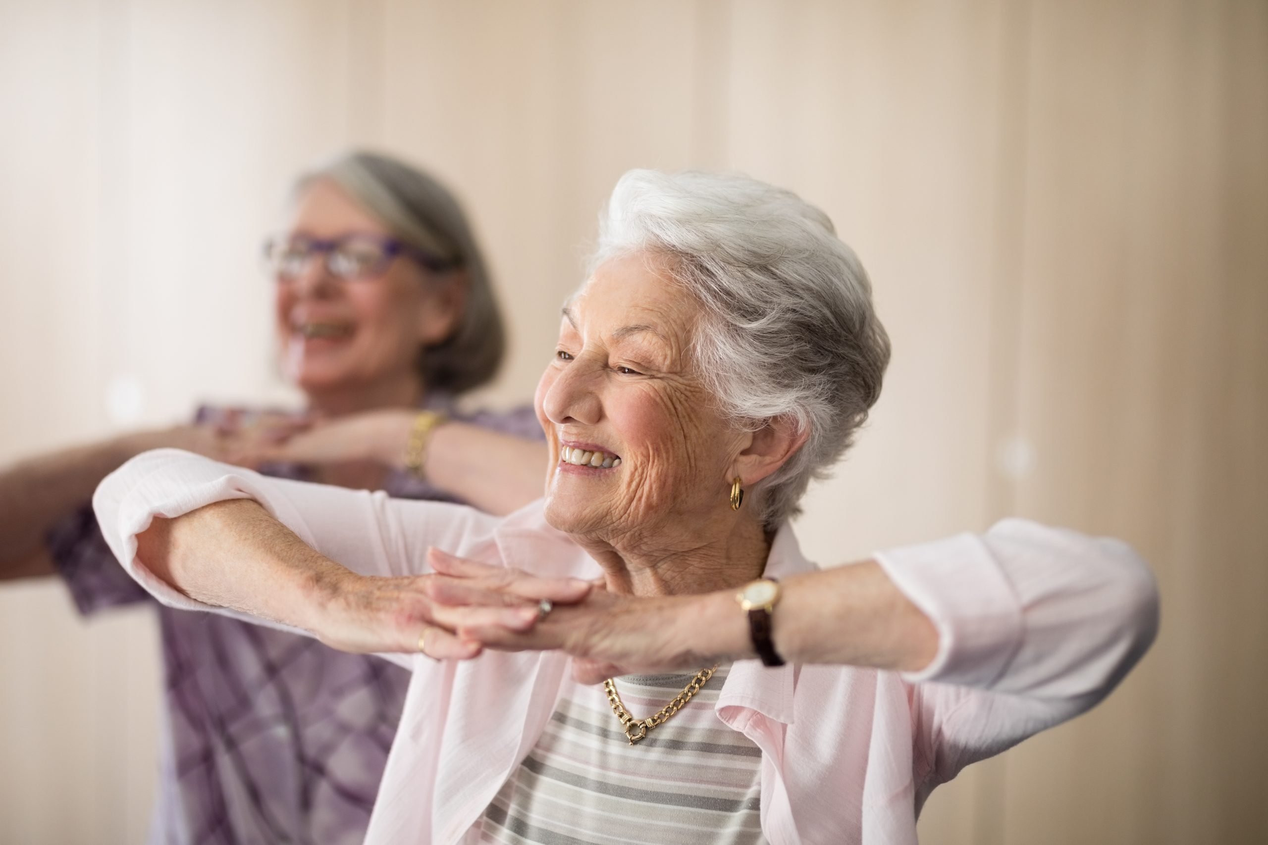 Smiling senior women with hands clasped looking away