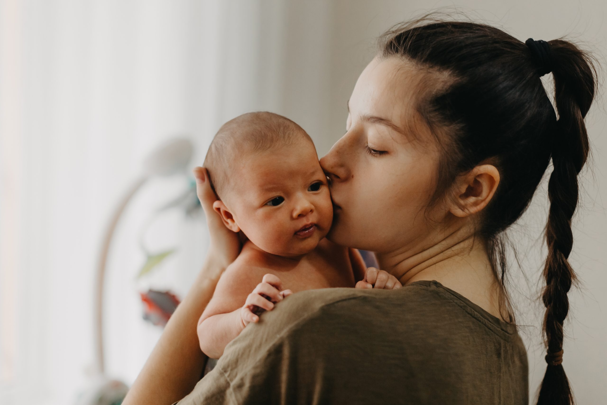 Loving mother carying of her newborn baby at home. Bright portra